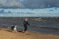 A girl runs with a husky dog Ã¢â¬â¹Ã¢â¬â¹on the beach on a windy autumn day Royalty Free Stock Photo